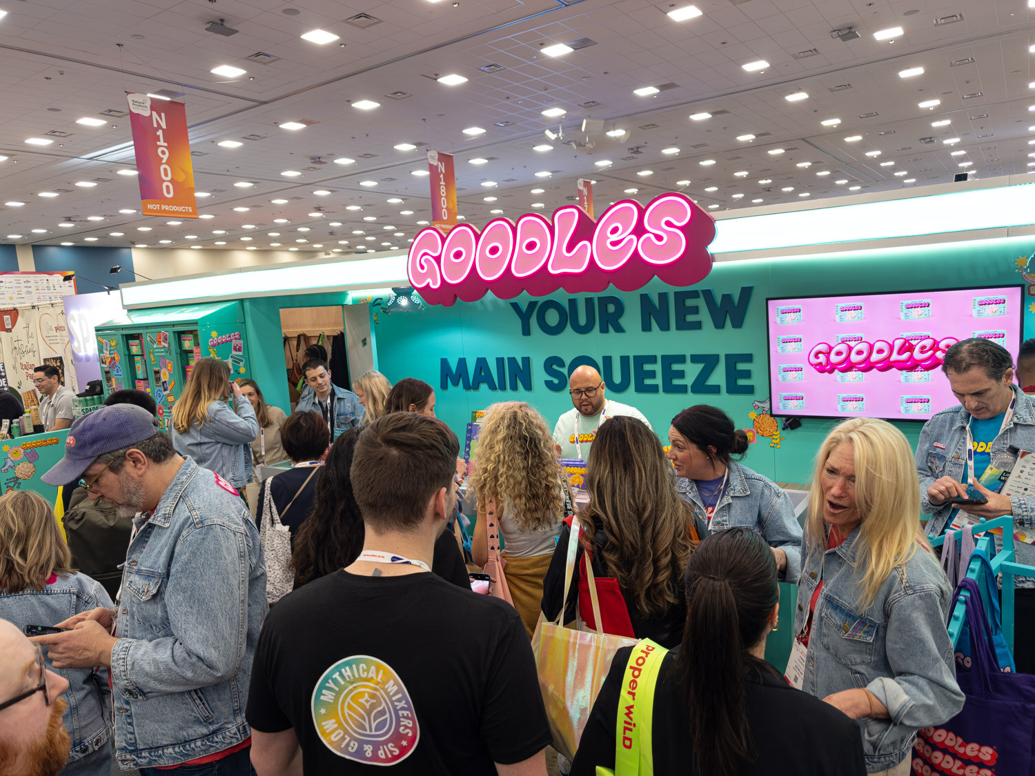 Attendees gathered around a teal Goodles booth with a sign reading Your New Main Squeeze