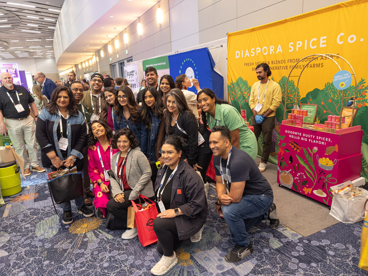 A group of people posing and kneeling in front of a Diaspora Spice Co. booth