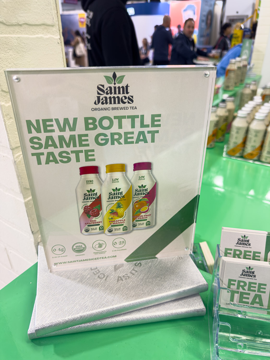 A Saint James Organic Brewed Tea sign reading New Bottle Same Great Taste on a green display