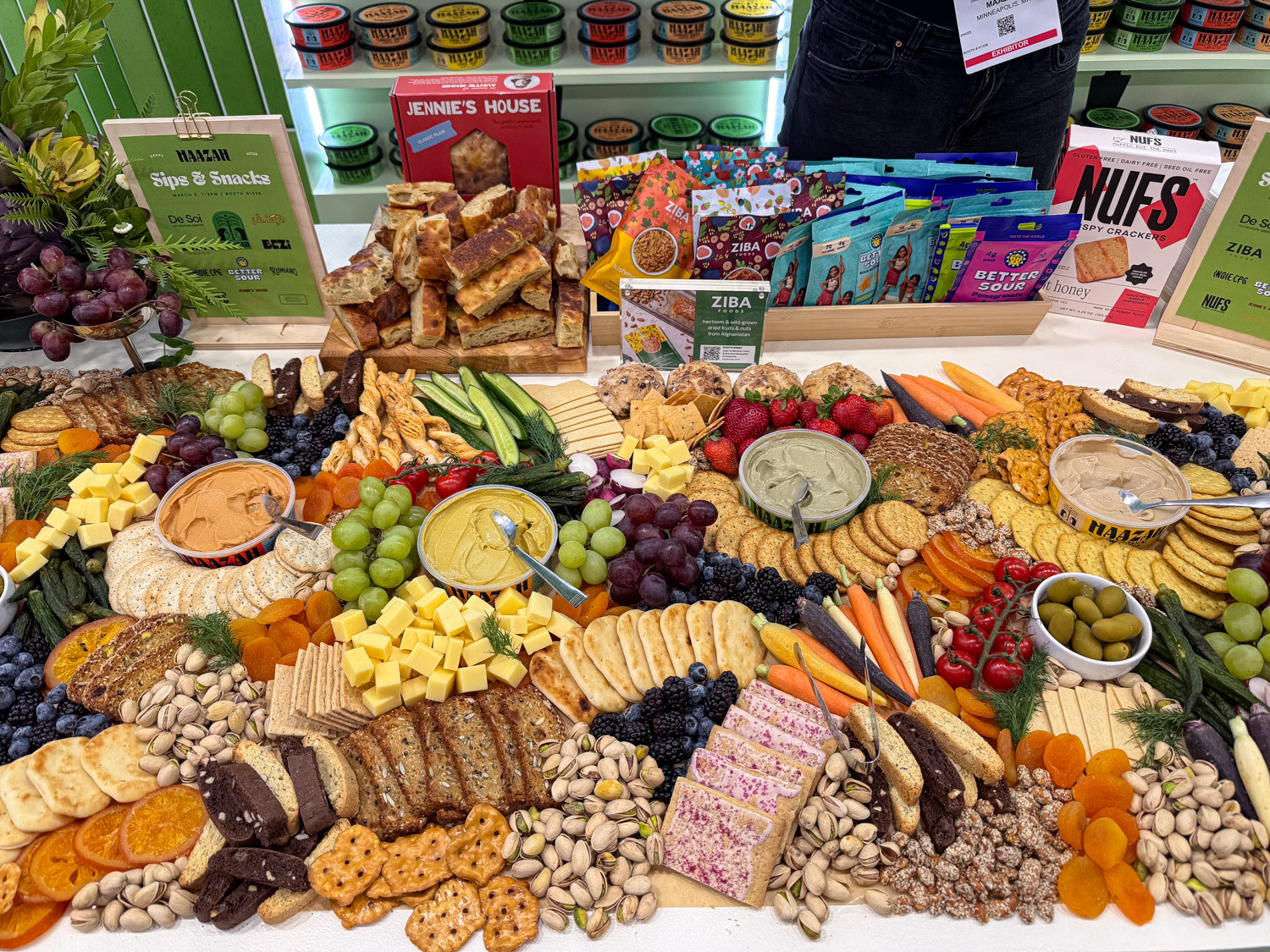 A large booth snack spread of dried fruit, nuts, crackers, vegetables and cheese