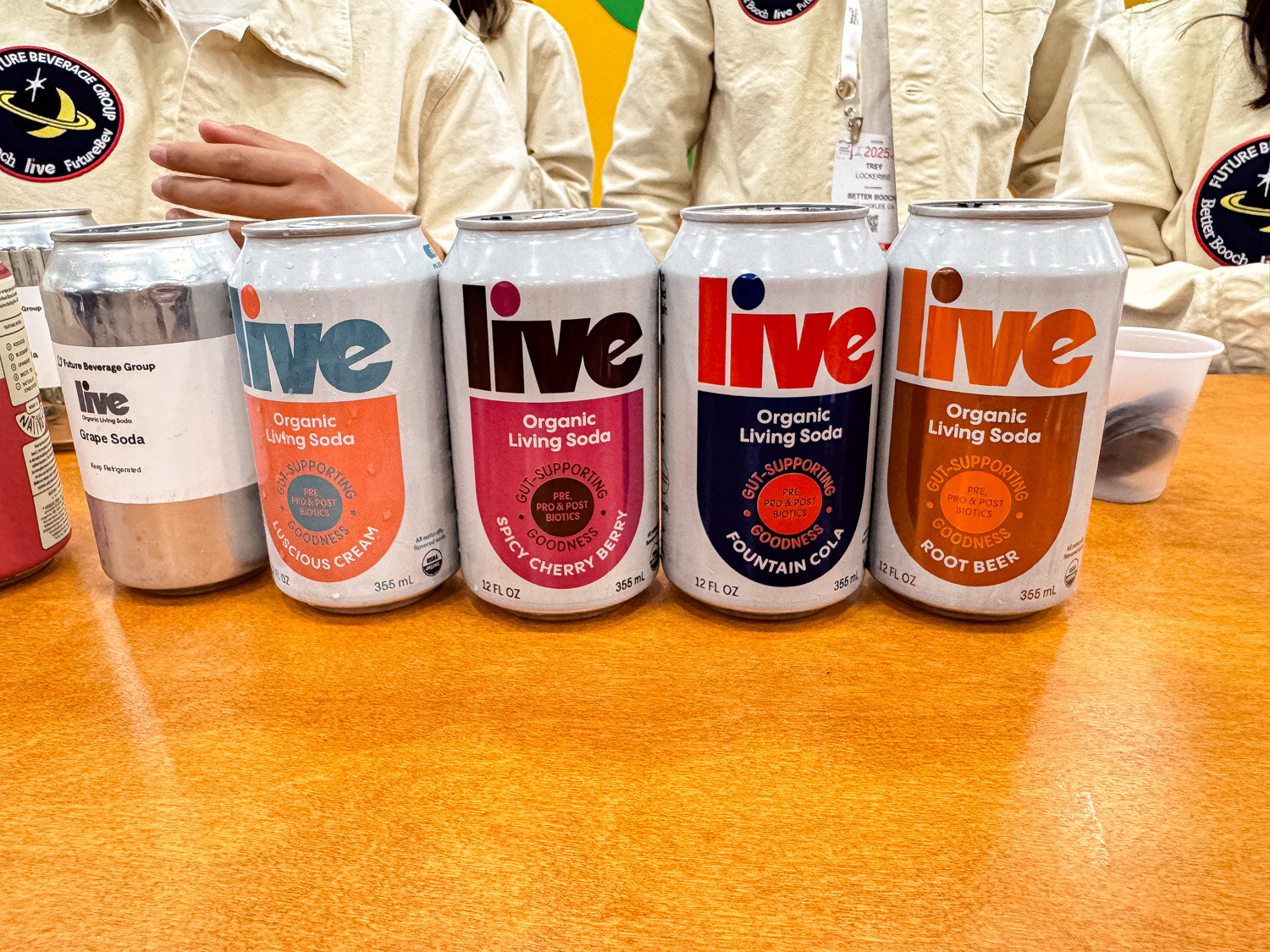 Five Live organic living soda cans in a row on an orange table