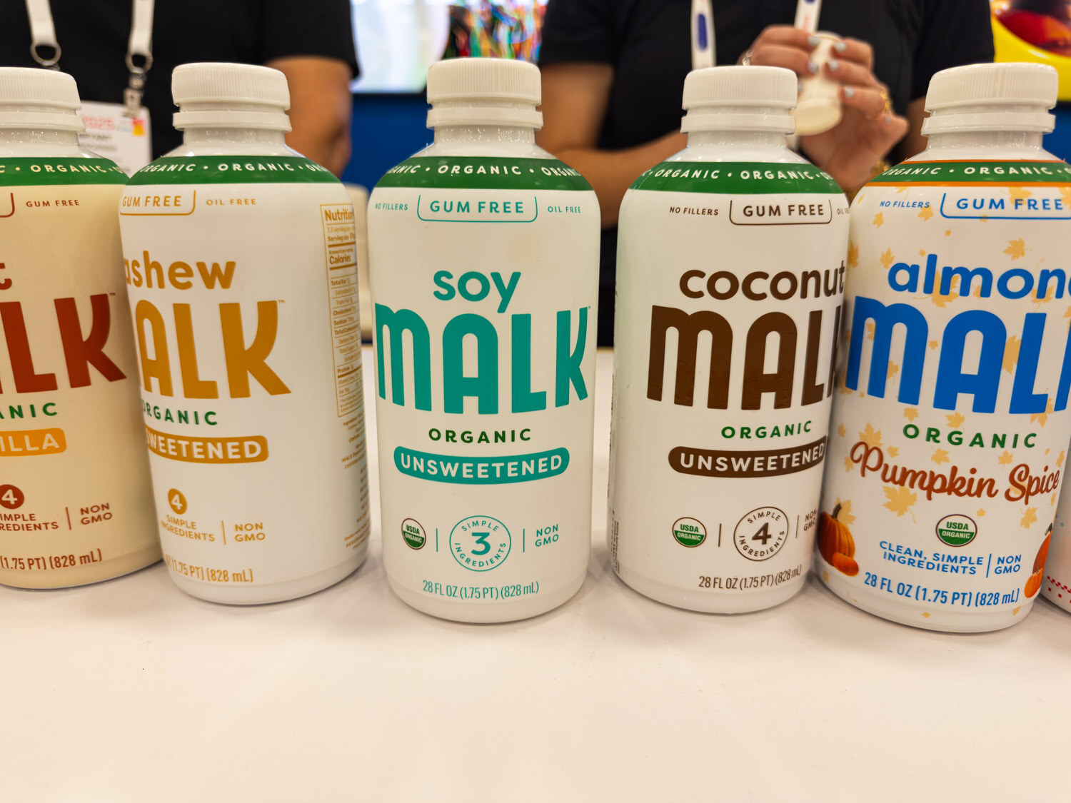 Four MALK organic milk bottles in cashew, soy, coconut and almond varieties on a white table