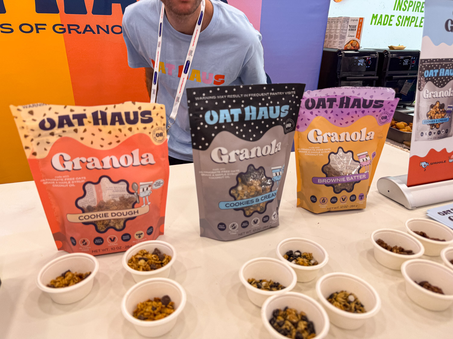 Oat Haus granola butter bags with sample cups on a table and a person behind