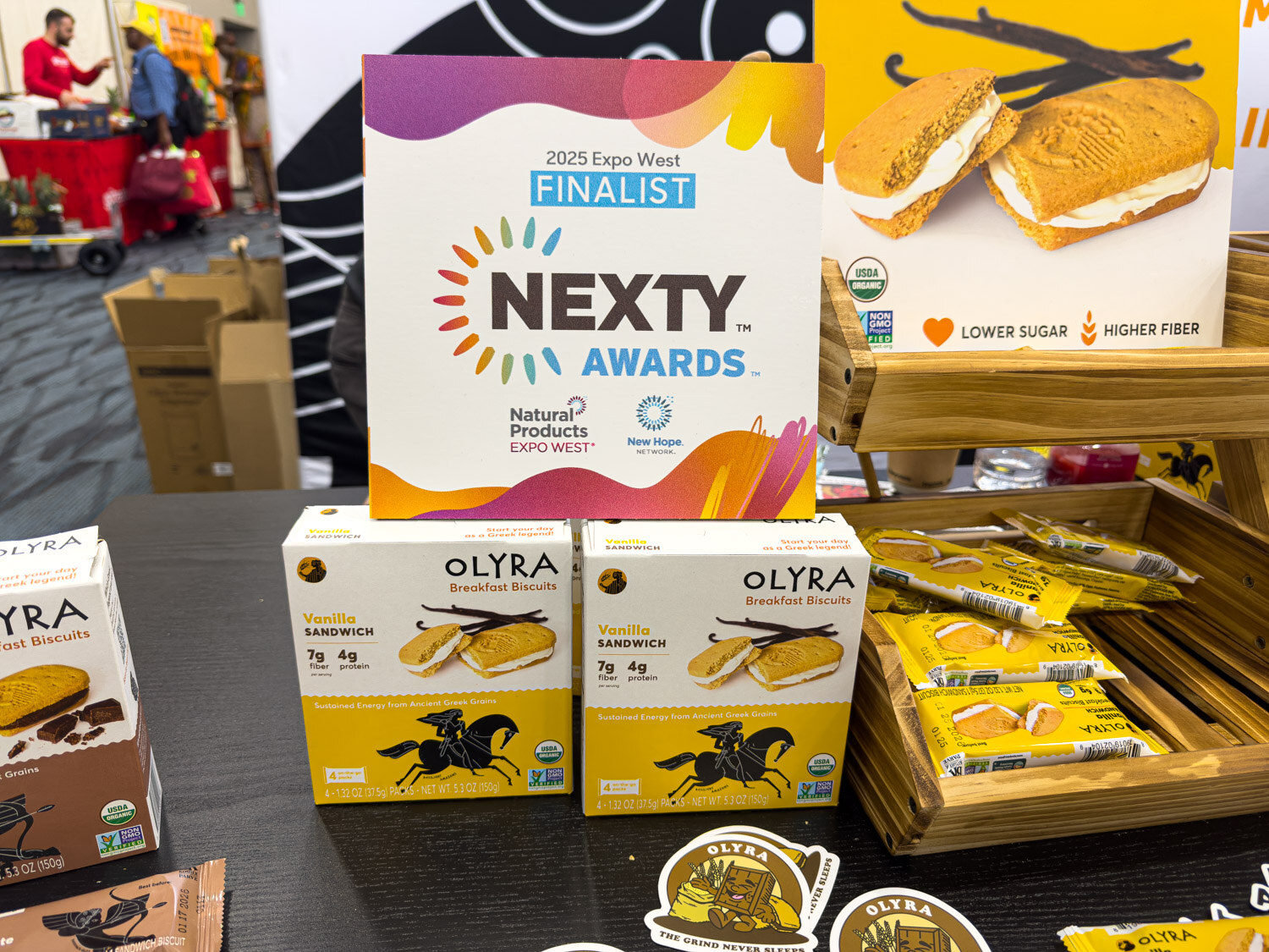 Olyra breakfast sandwich products next to a 2025 Expo West Nexty Awards Finalist sign