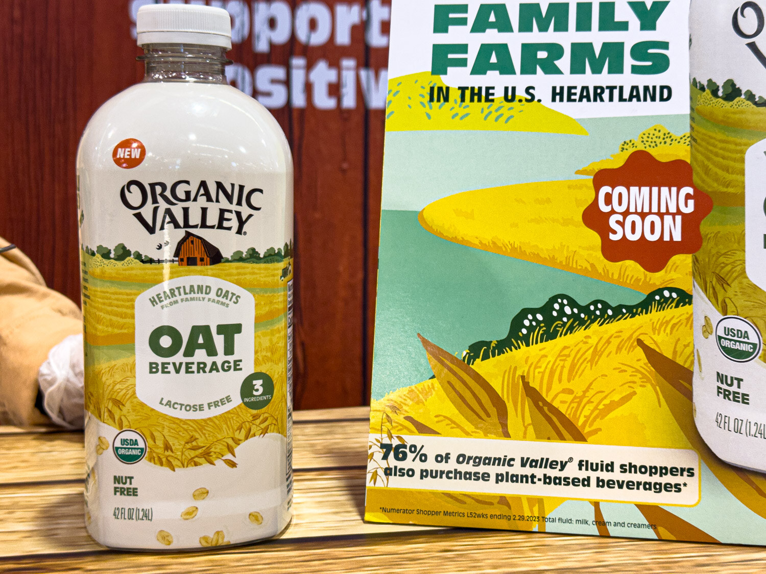 A bottle of Organic Valley oat beverage next to a Coming Soon sign about family farms