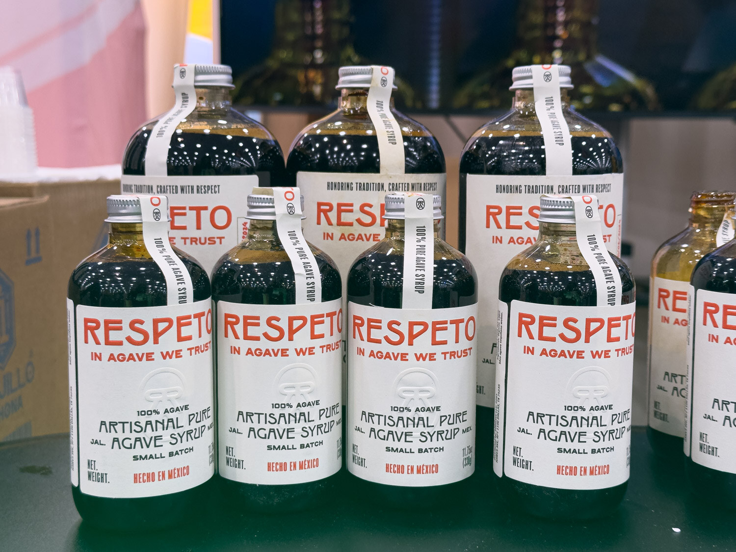 Several bottles of Respeto artisanal pure agave syrup on a dark shelf