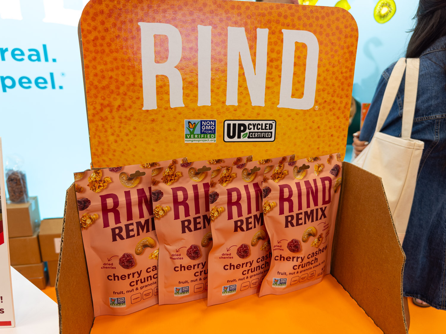A Rind Remix upcycled fruit snack display in an orange cardboard stand