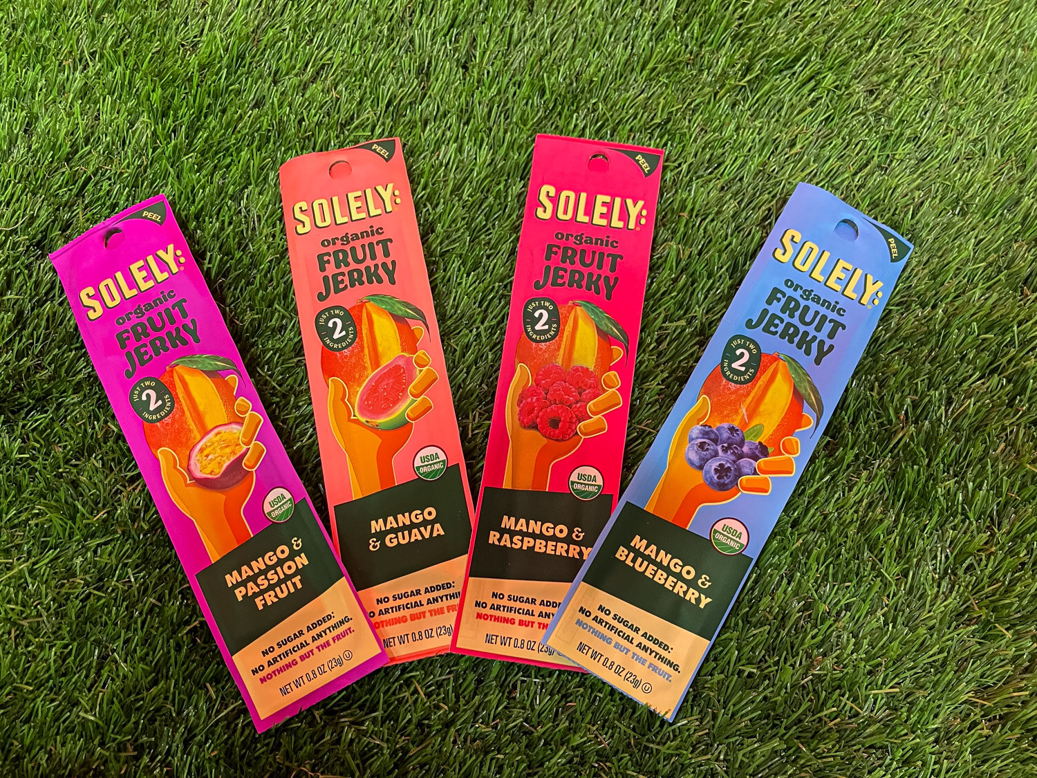 Four packs of Solely organic fruit jerky arranged on artificial grass