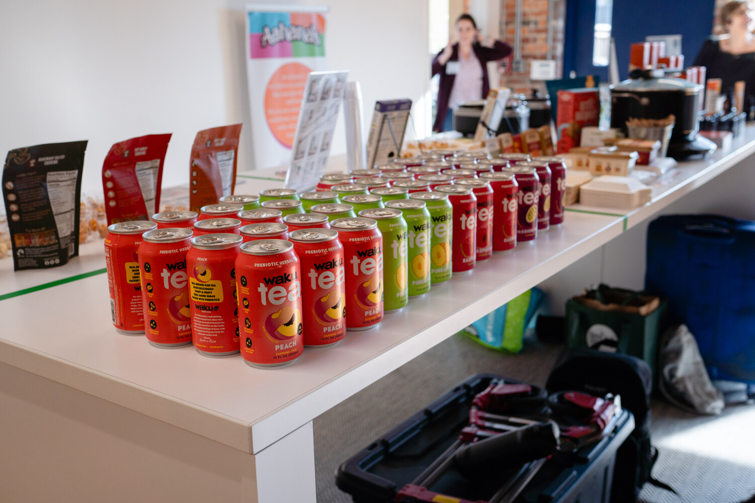 Red, green and orange cans of tea lined up in rows on a white table.