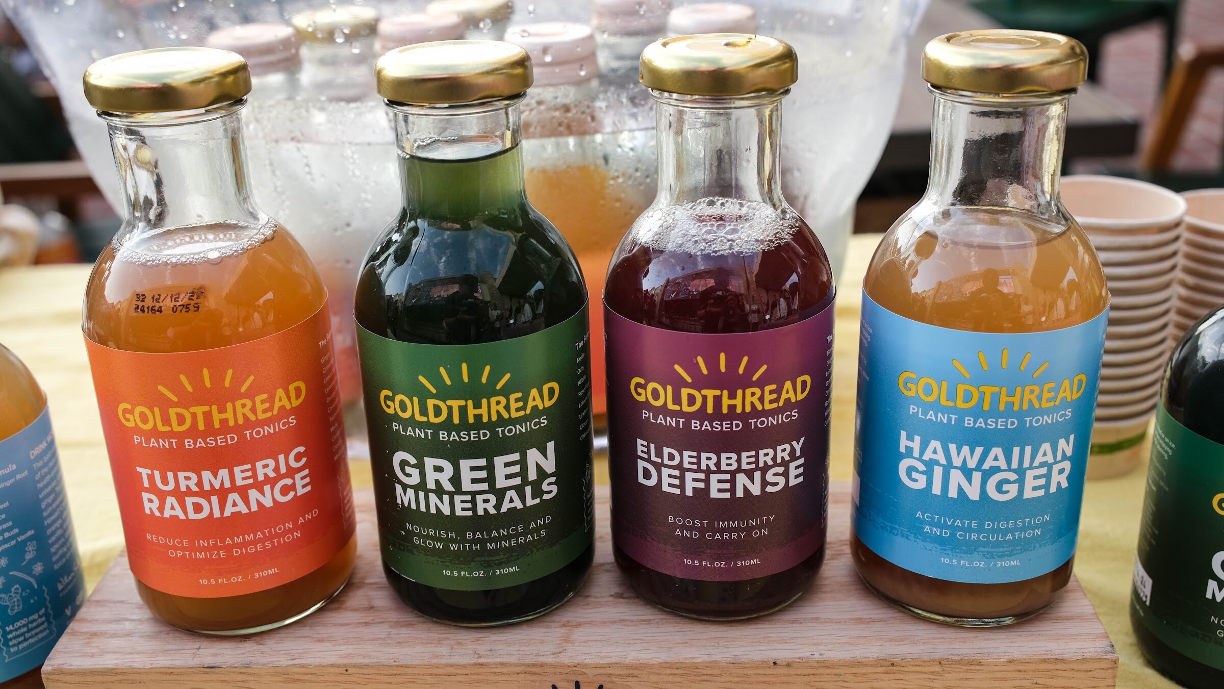 Four bottles labeled Goldthread plant-based tonics, in turmeric, green minerals, elderberry and Hawaiian ginger flavors.
