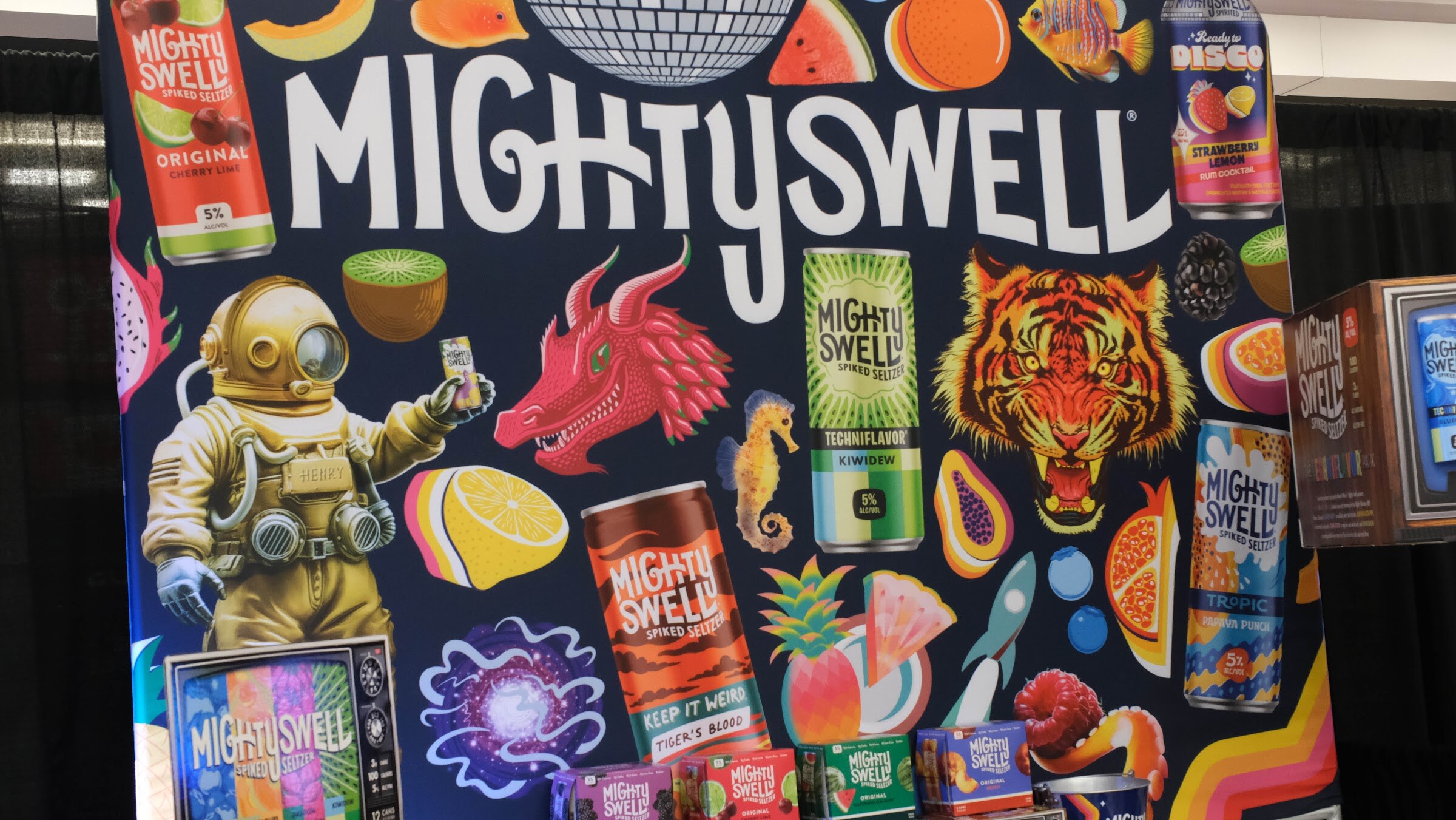 Large illustrated Mighty Swell booth graphic with cans, an astronaut and a tiger.