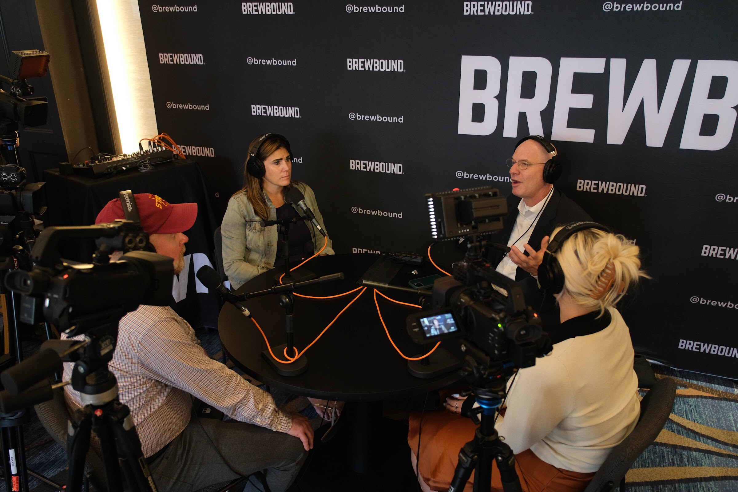 High angle on the Brewbound Podcast set with a host and guest at a table surrounded by video cameras and crew.