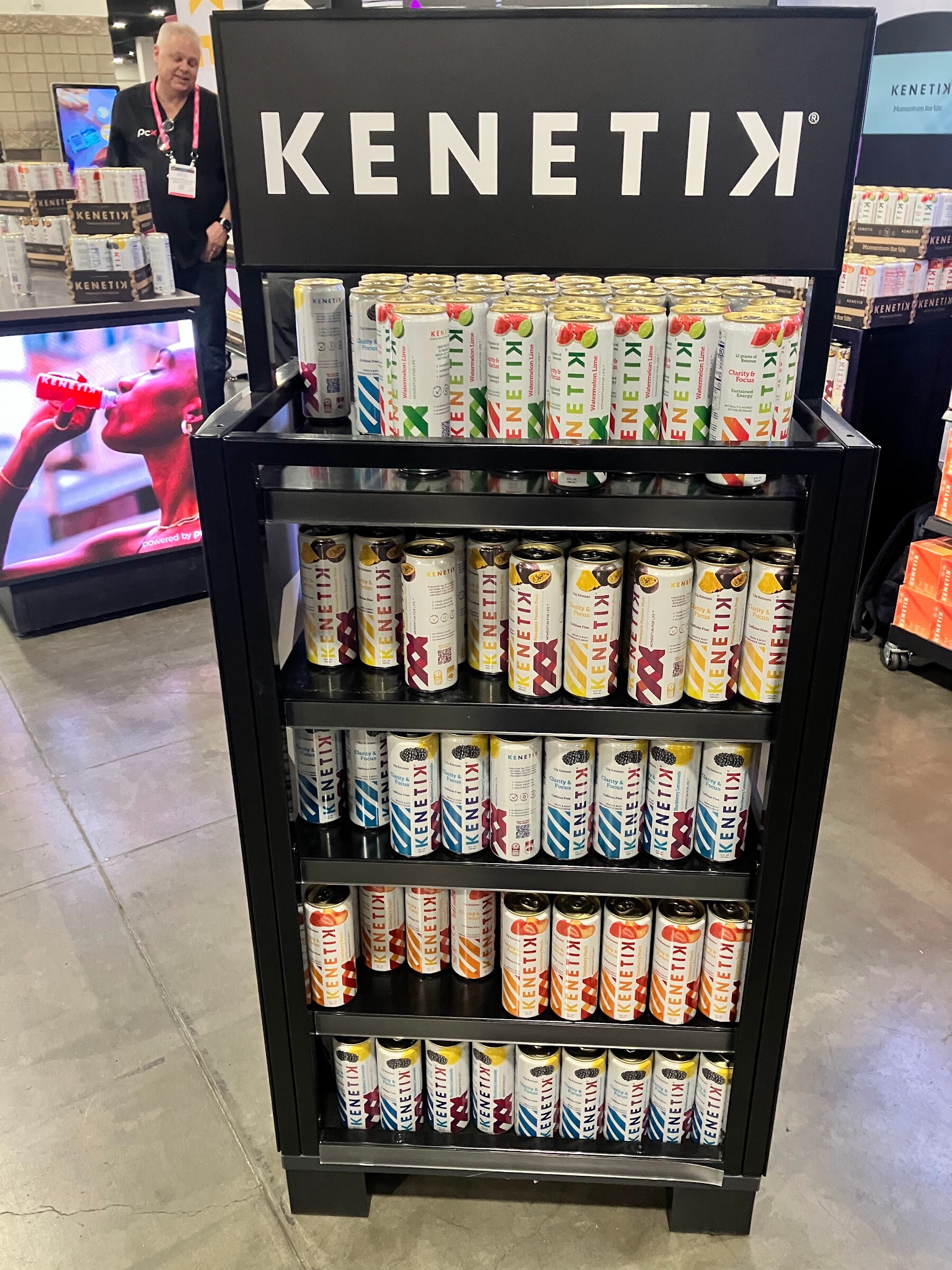 Black Kenetik shelf display filled with rows of Kenetik cans on the show floor.