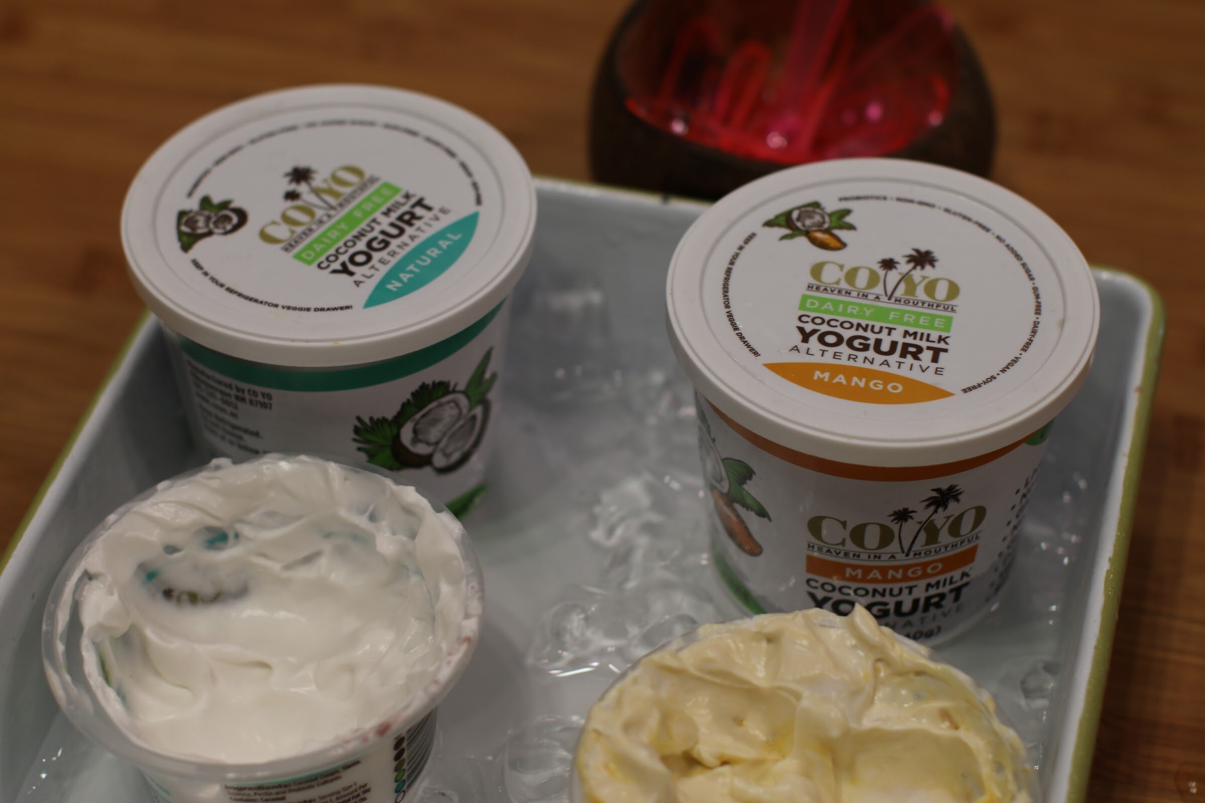 Two tubs of Coyo coconut milk yogurt on ice in a tray beside two open sample cups.