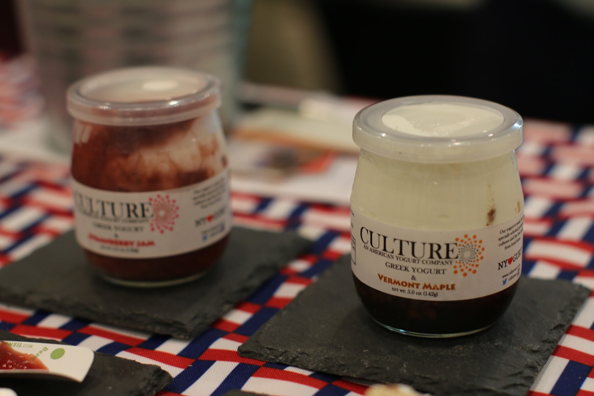 Two glass jars of Culture Greek yogurt on slate squares over a red, white and blue tablecloth.