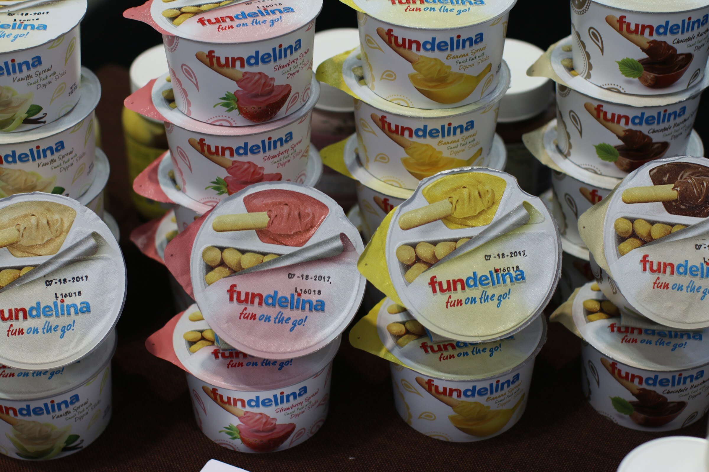 Stacked Fundelina snack cups with colorful peel-off lids showing sweet spreads and dipping sticks.