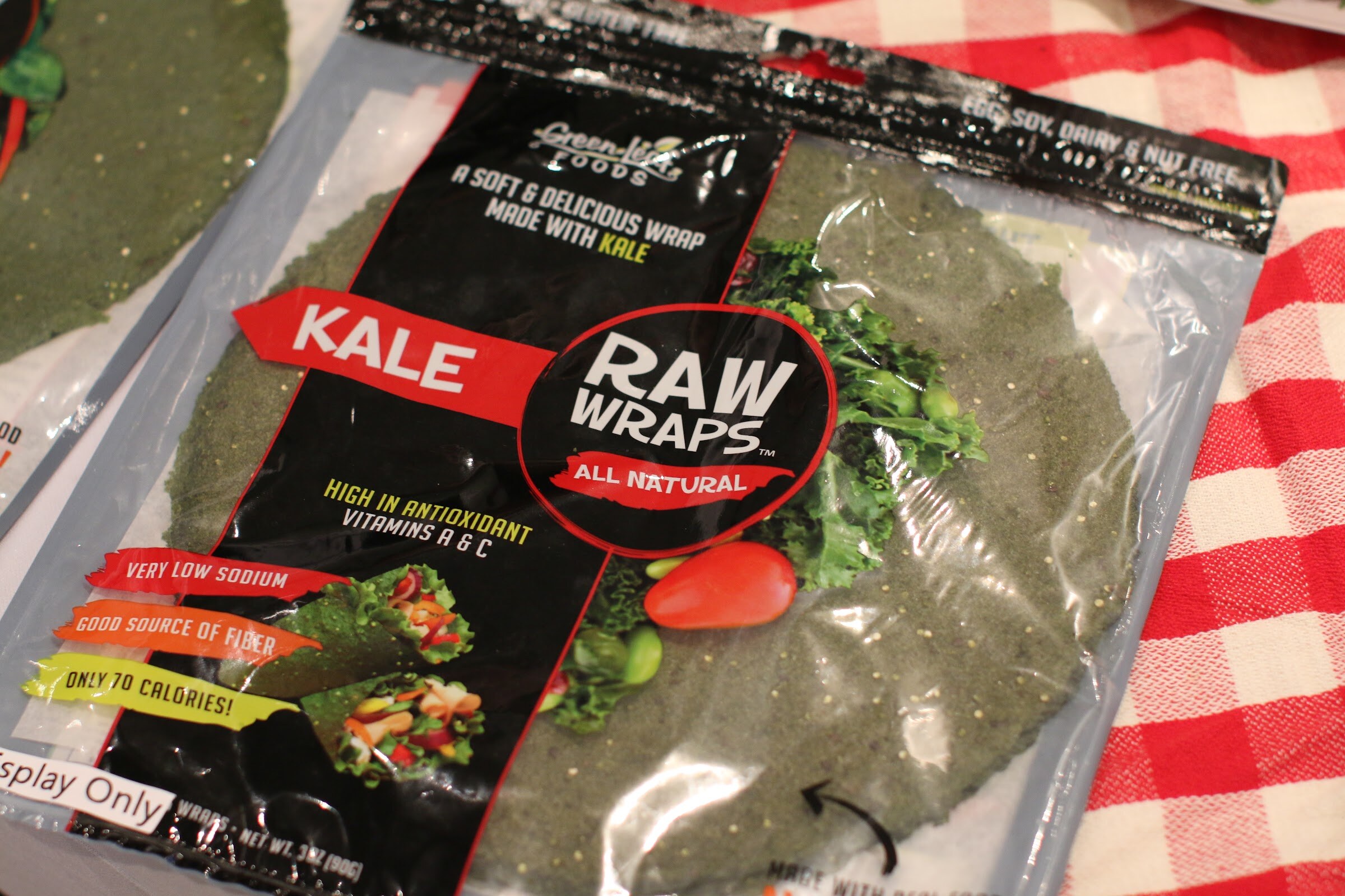 Close view of a Raw Wraps kale wrap package with a green wrap visible through the clear front.