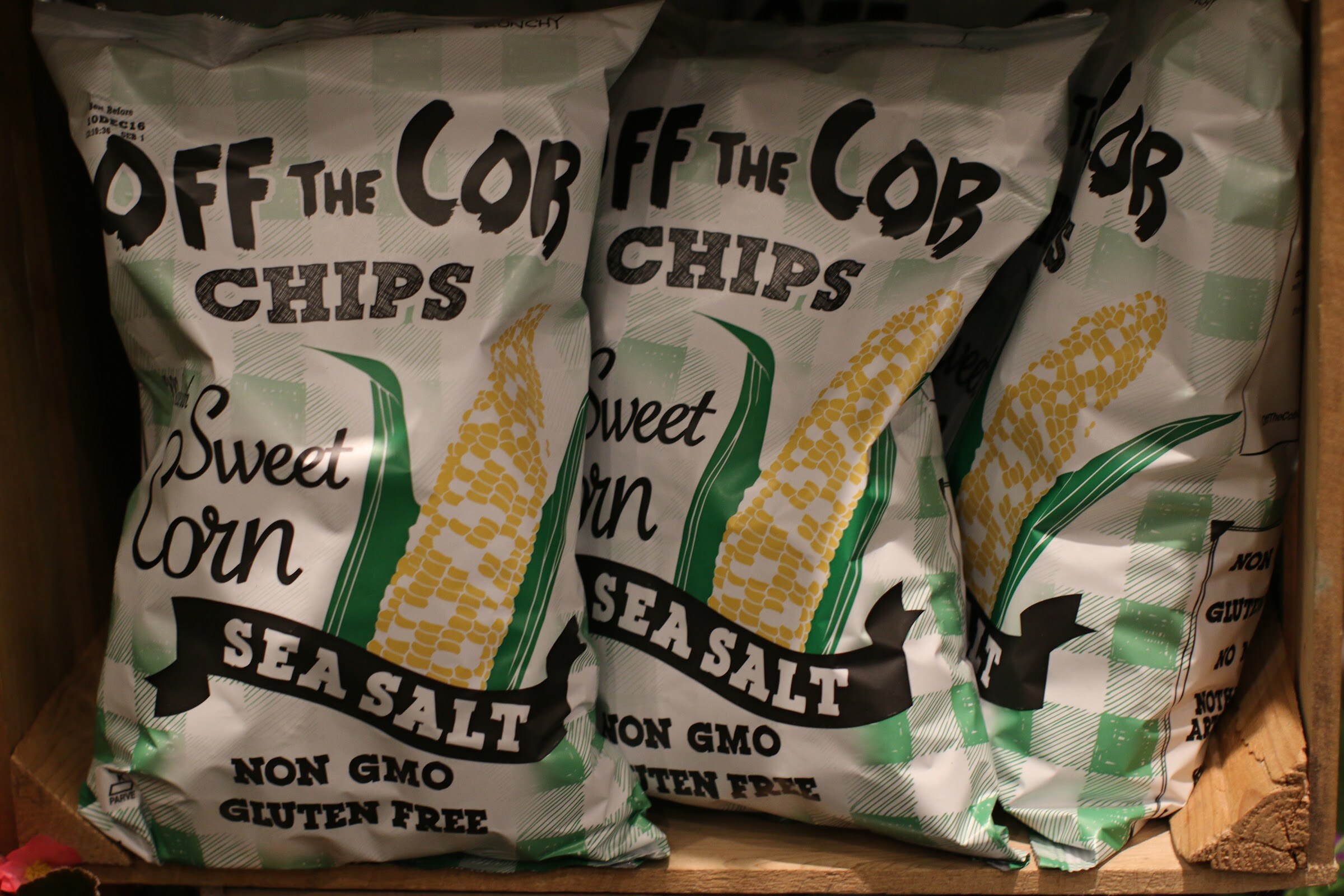 Three bags of Off the Cob sweet corn sea salt chips in a wooden crate.