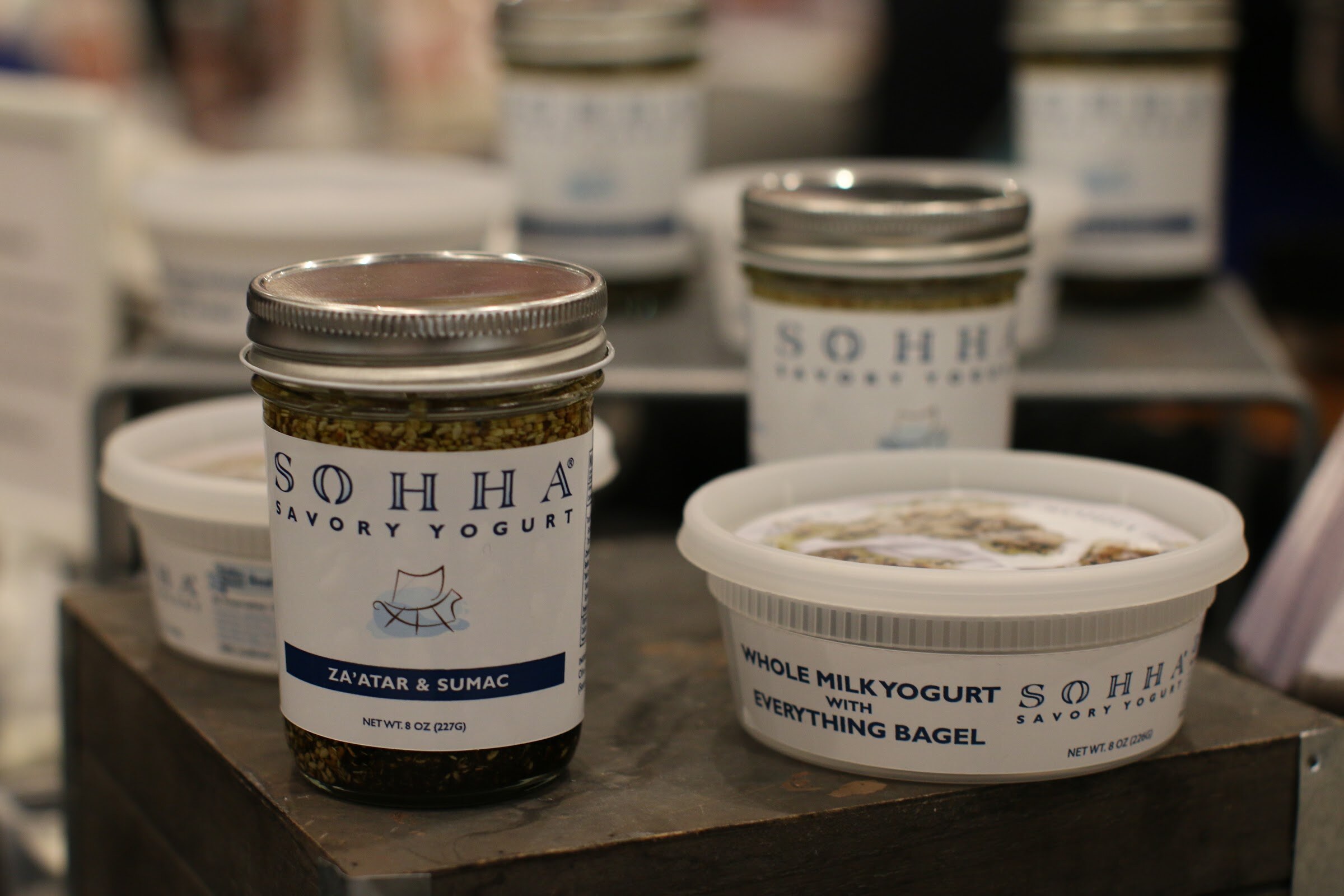 A jar of SOHHA savory yogurt with za'atar and sumac beside a tub labeled whole milk yogurt with everything bagel.