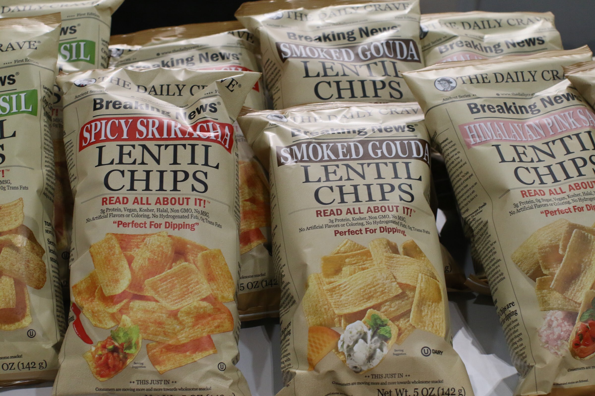 Rows of cream-colored The Daily Crave lentil chip bags in several flavors.