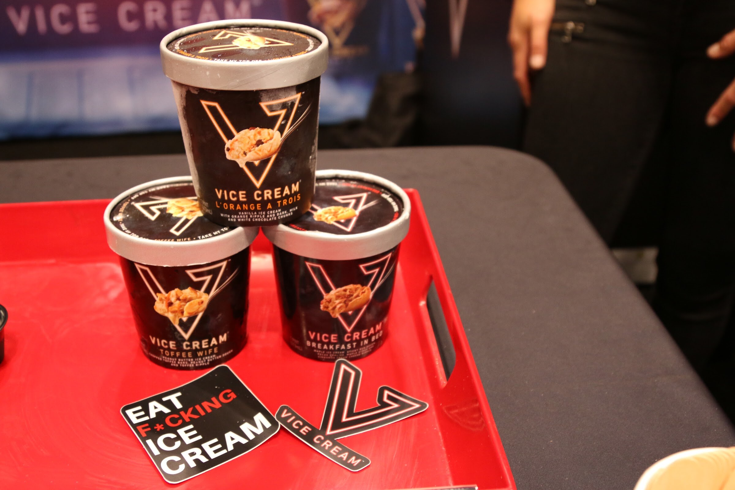 Three black Vice Cream ice cream pints stacked on a red tray beside Vice Cream stickers.