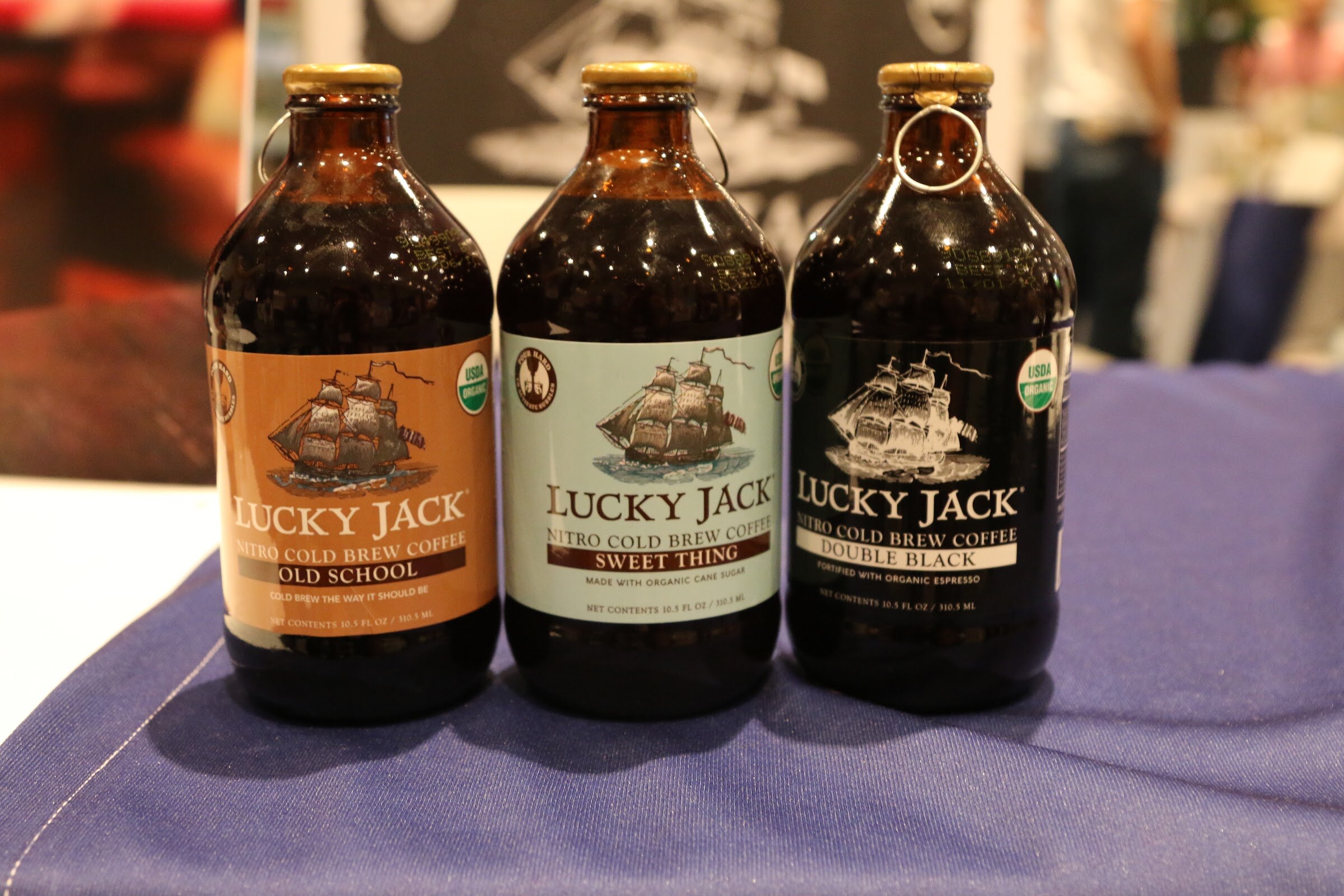 Three amber glass Lucky Jack nitro cold brew coffee bottles with orange, white and black labels.