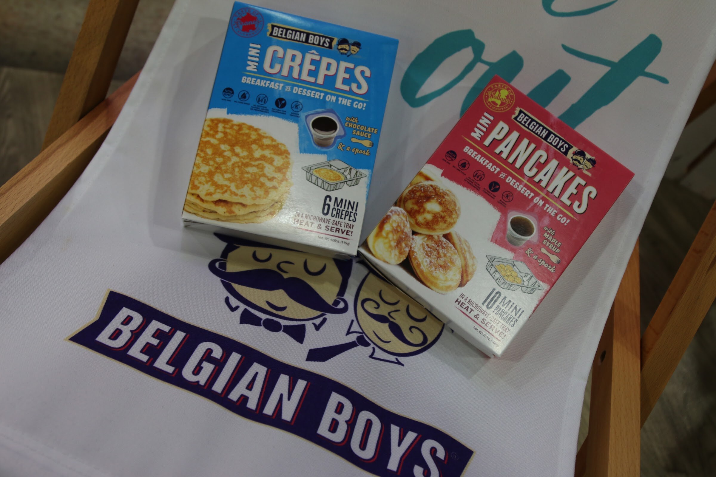 Two boxes, blue Mini Crepes and red Mini Pancakes, on white fabric with a Belgian Boys logo.