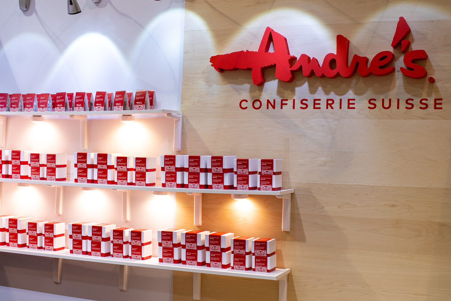 A wall of red-and-white boxes under a red Andre's Confiserie Suisse sign.