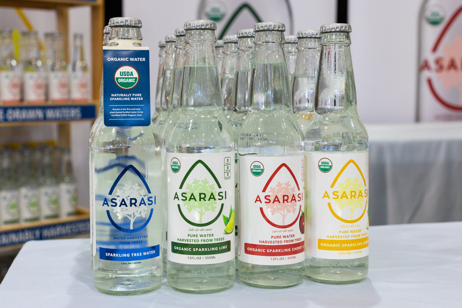 Four flavors of Asarasi in glass bottles on a white table.