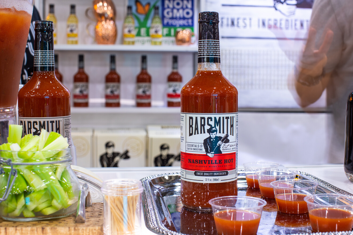Bottles of Barsmith Nashville Hot mix with cups of red drink and celery sticks.