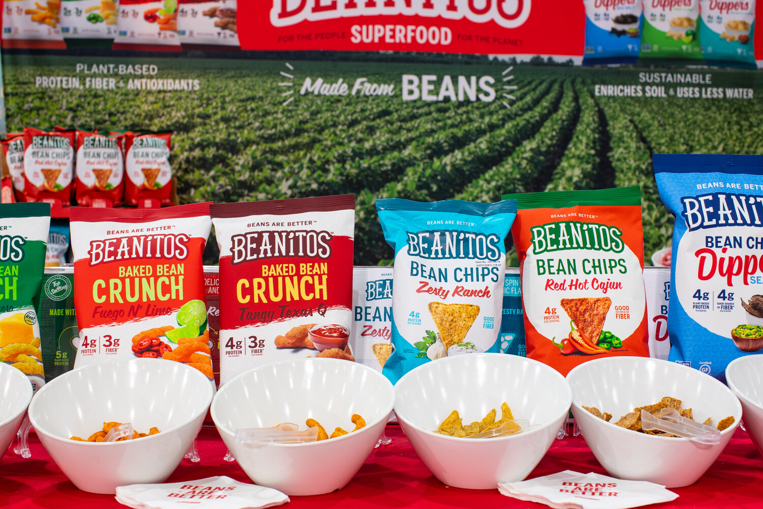 Bags of Beanitos in front of a field backdrop with white bowls.