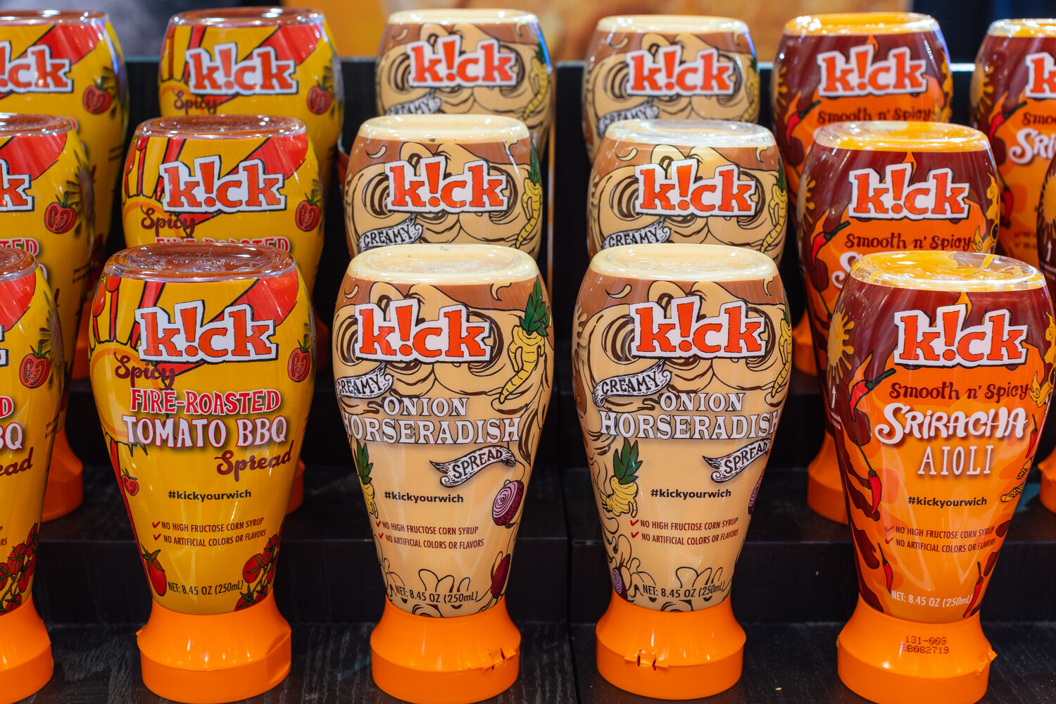 Rows of k!ck bottles in Tomato BBQ, Onion Horseradish and Sriracha Aioli.