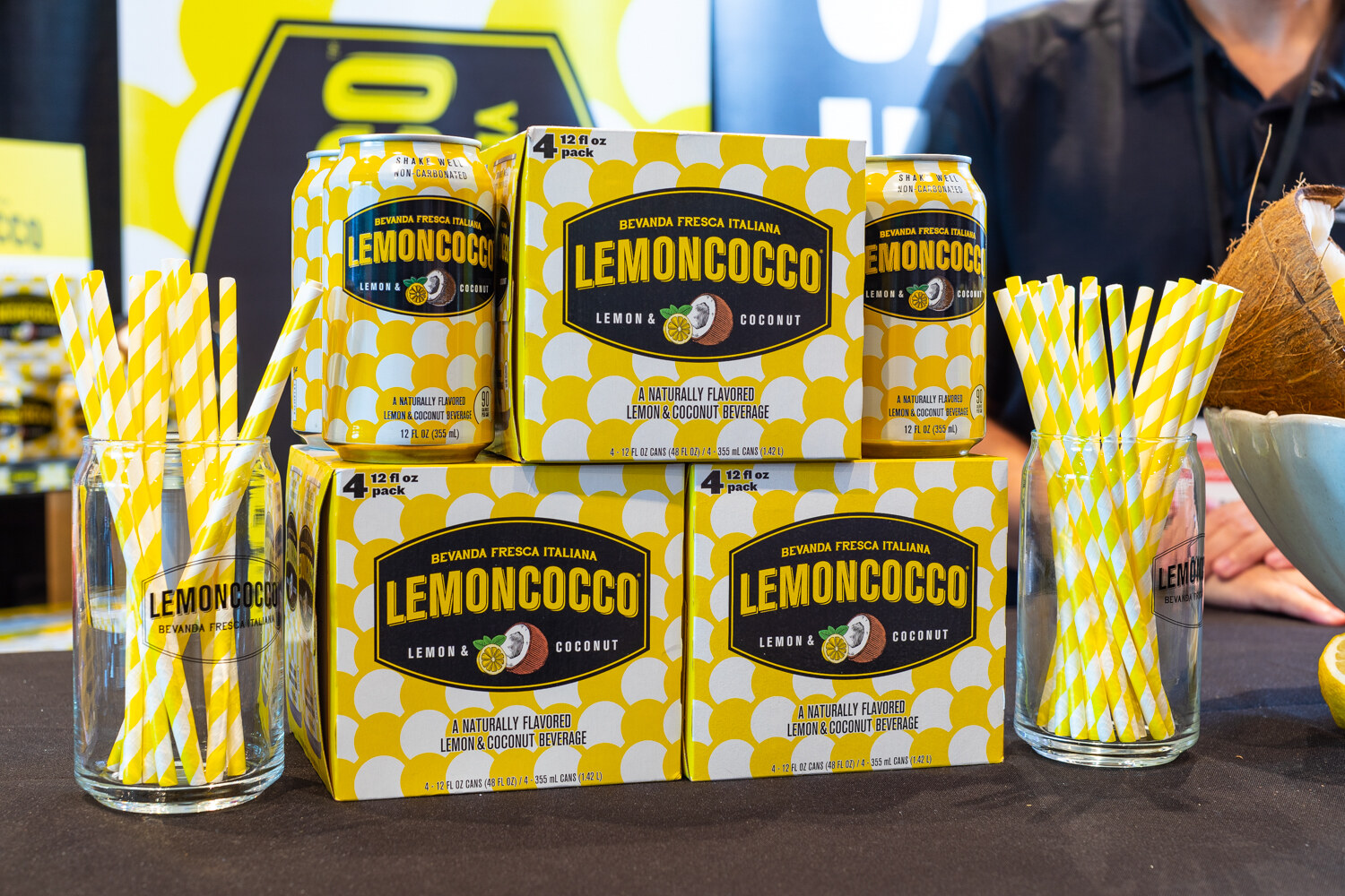 Cases and cans of Lemoncocco with yellow-and-white striped straws.