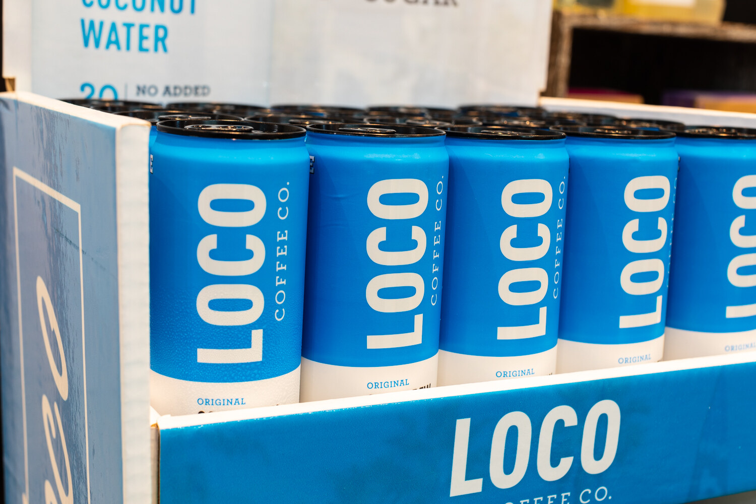 Blue cans labeled Loco Coffee Co. in a cardboard display.