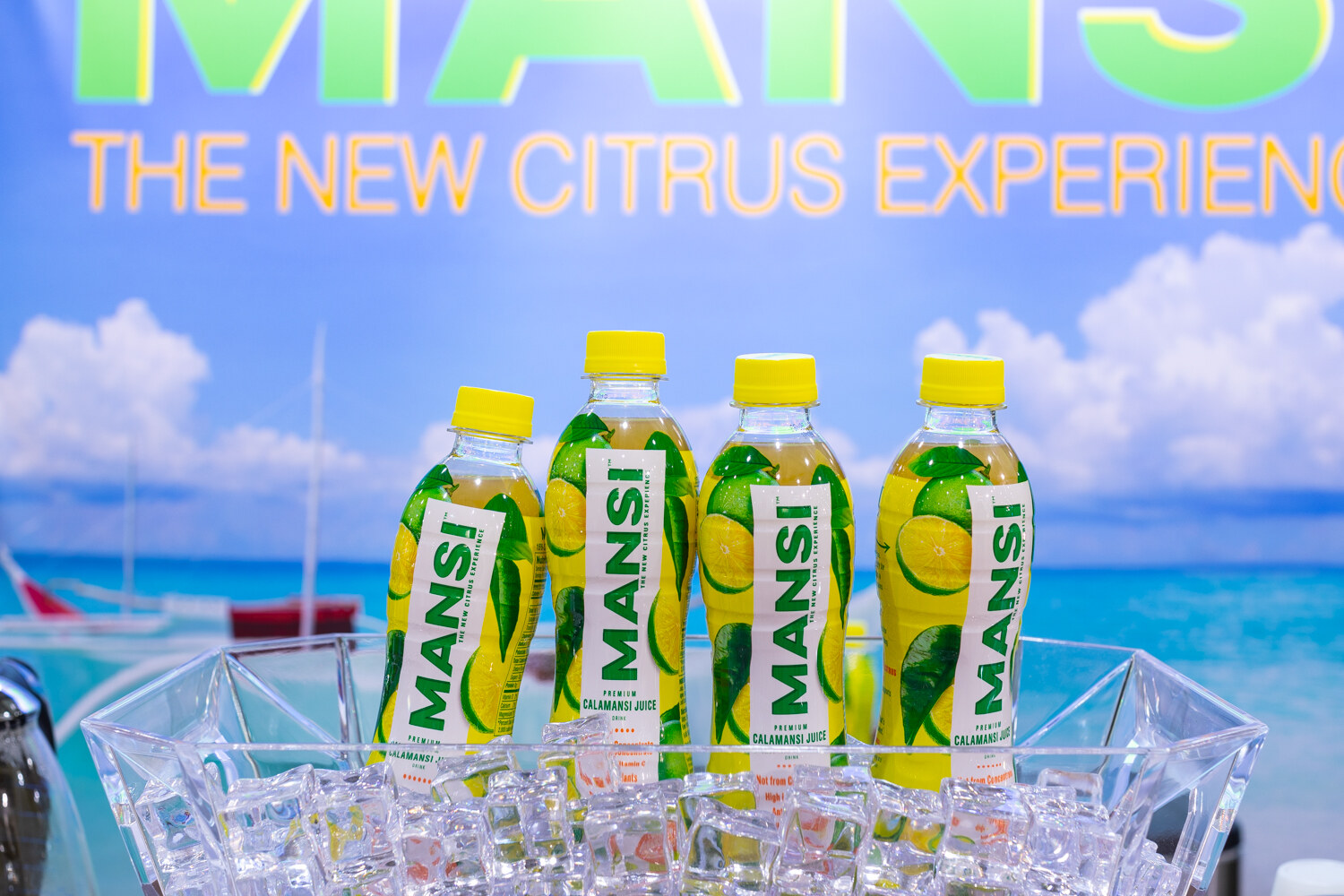 Four Mansi bottles on ice with a tropical backdrop.