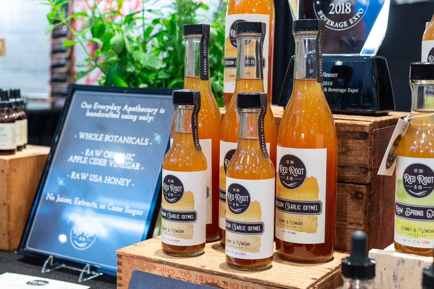 Bottles of Red Root tonic on a wooden crate beside a sign about its ingredients.