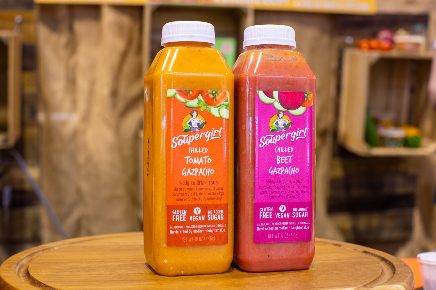 Two bottles of Soupergirl gazpacho on a wooden platter.