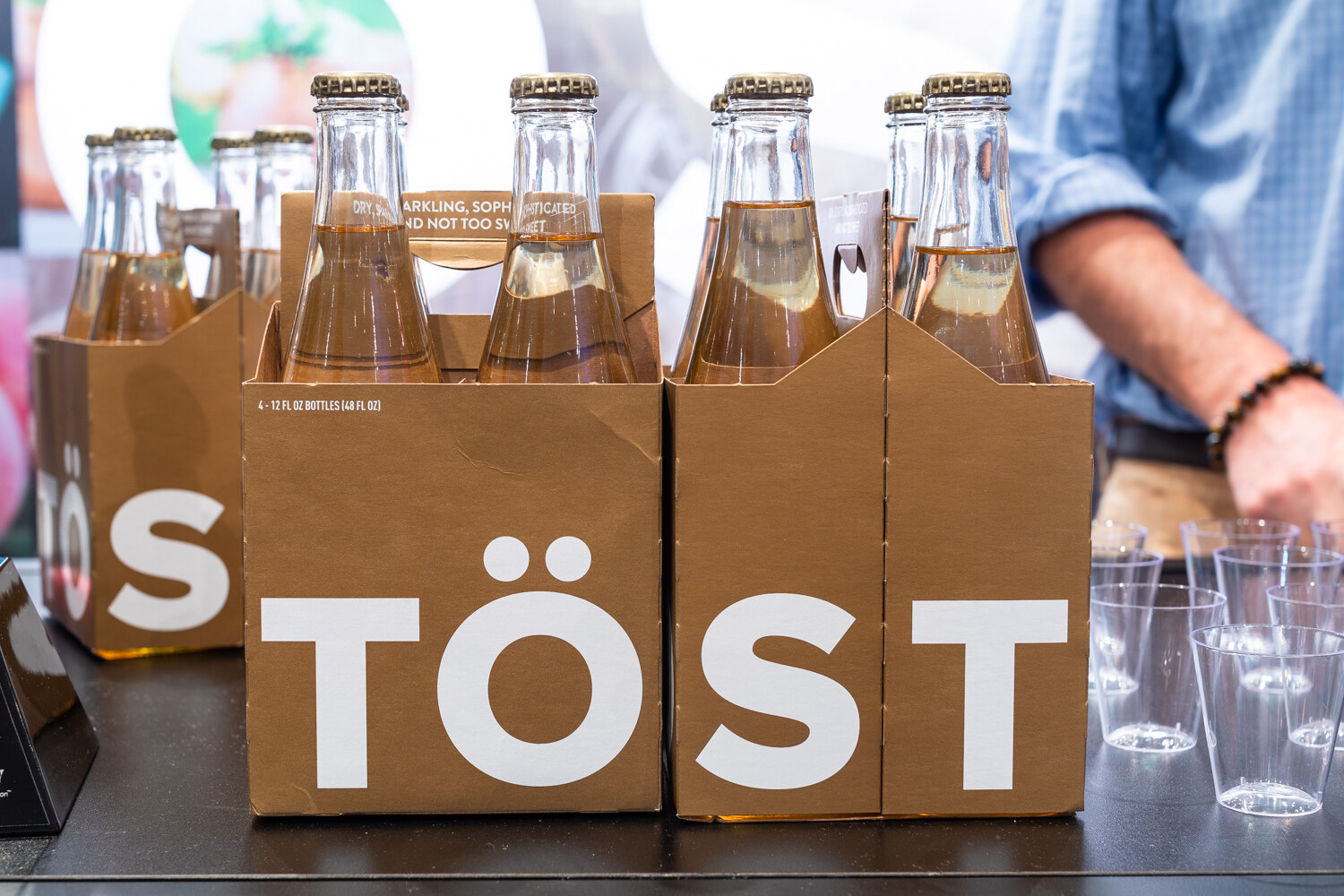 Cardboard four-packs marked TOST with glass bottles.