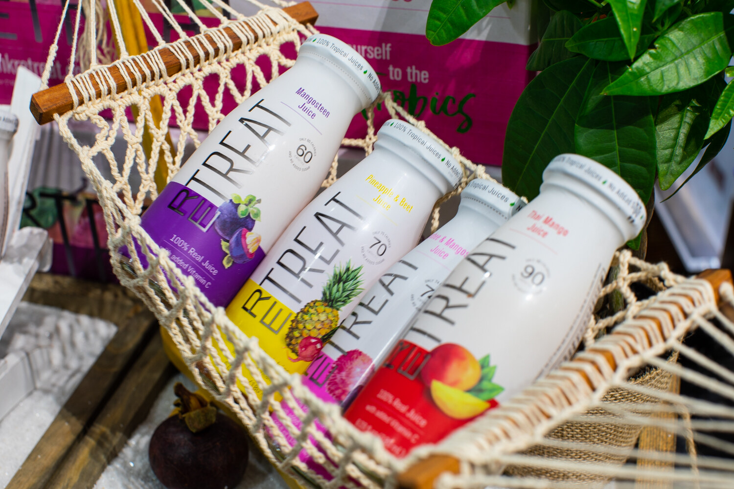 Four bottles of Treat juice in a rope hammock with tropical fruit.