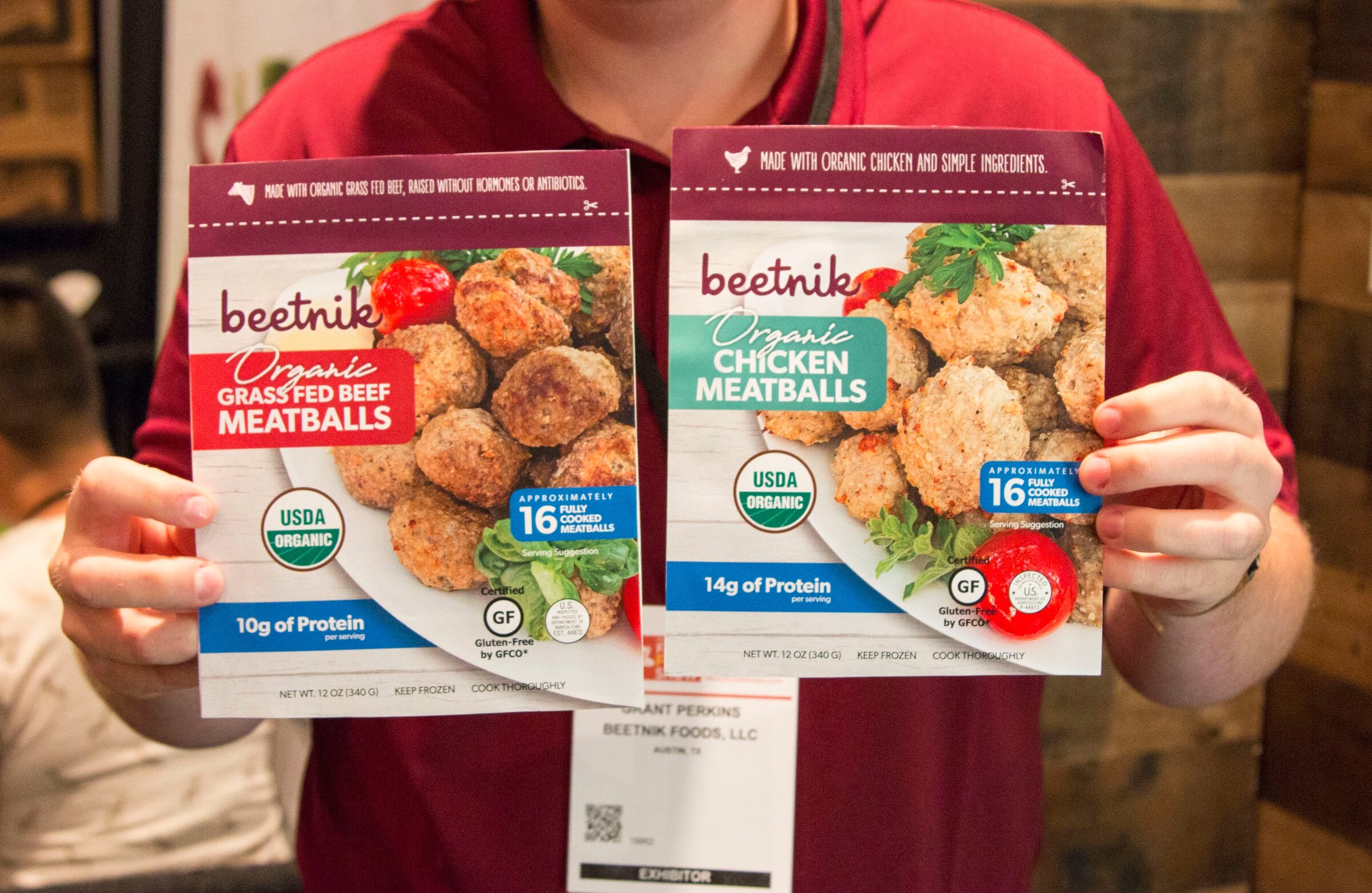 Photo of an exhibitor holding beetnik grass-fed beef and chicken meatball packages.