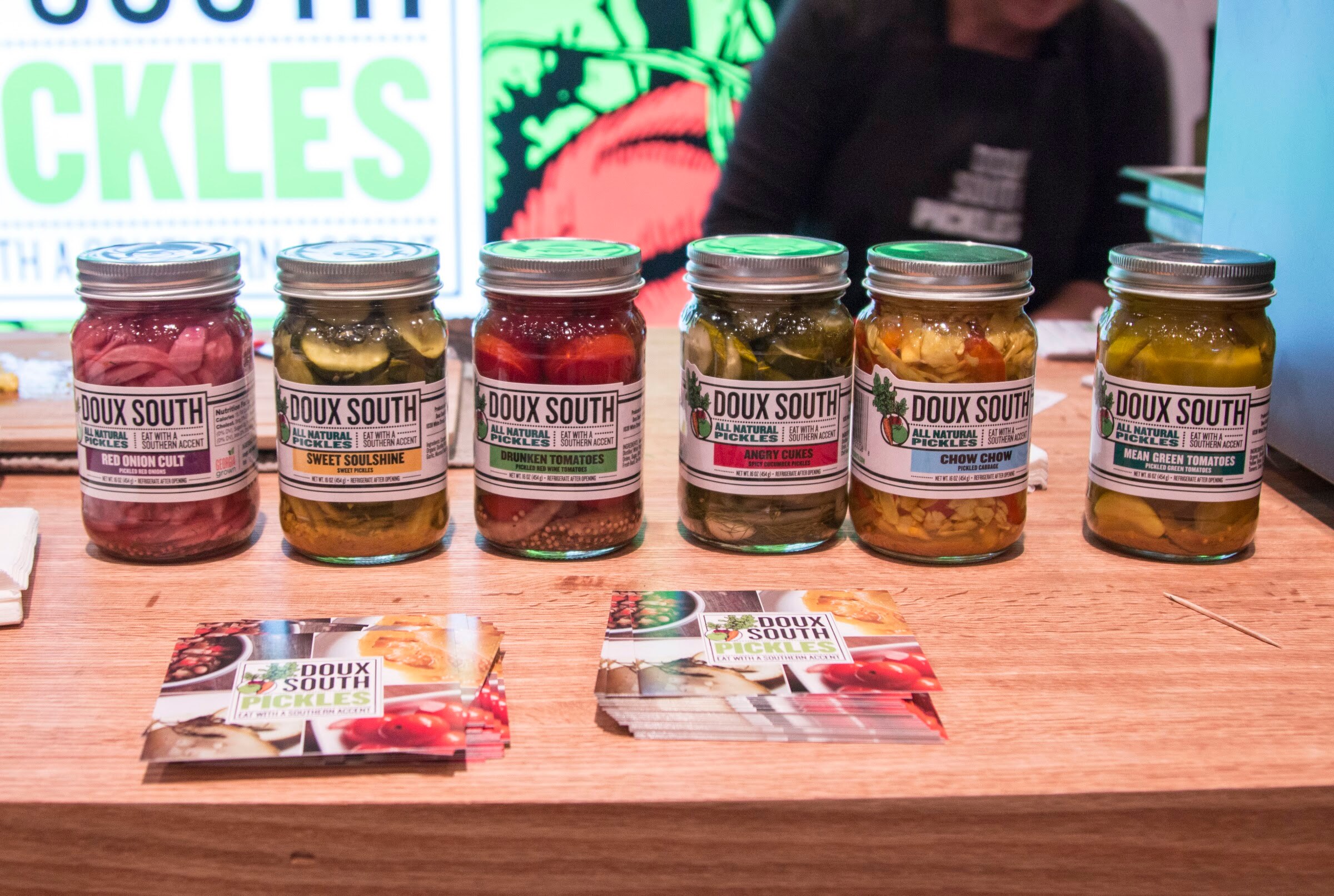 Photo of Doux South pickle jars on a wooden table.
