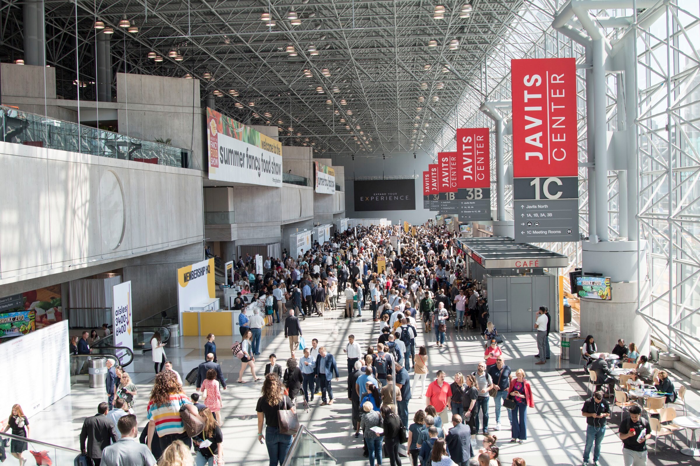 Photo of a crowded concourse at the Javits Center under Javits Center banners.