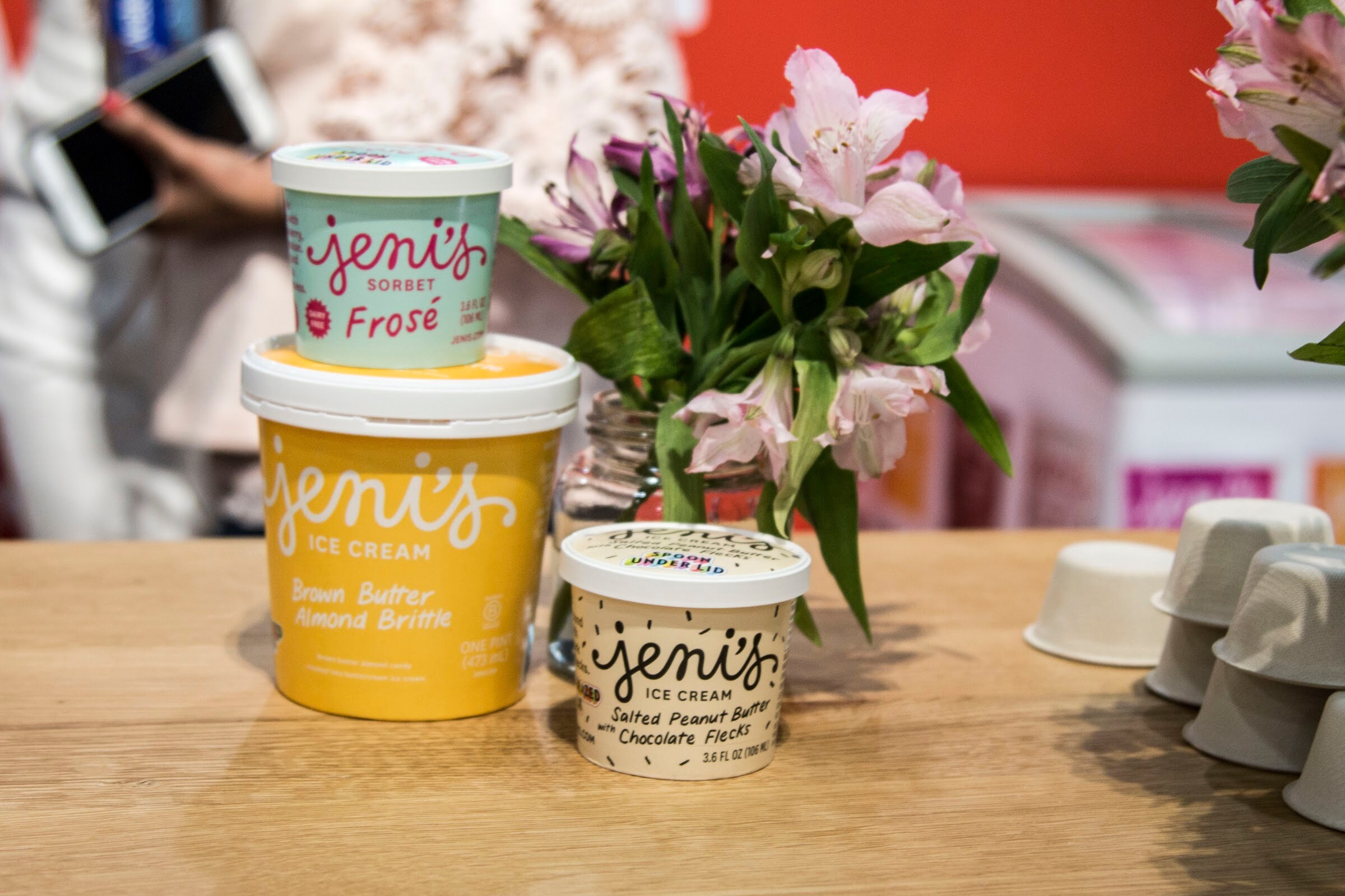 Photo of Jeni's ice cream pints and sorbet on a counter with flowers.