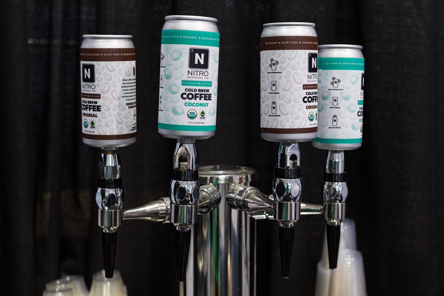 Photo of nitro cold brew coffee cans hanging from stainless taps.