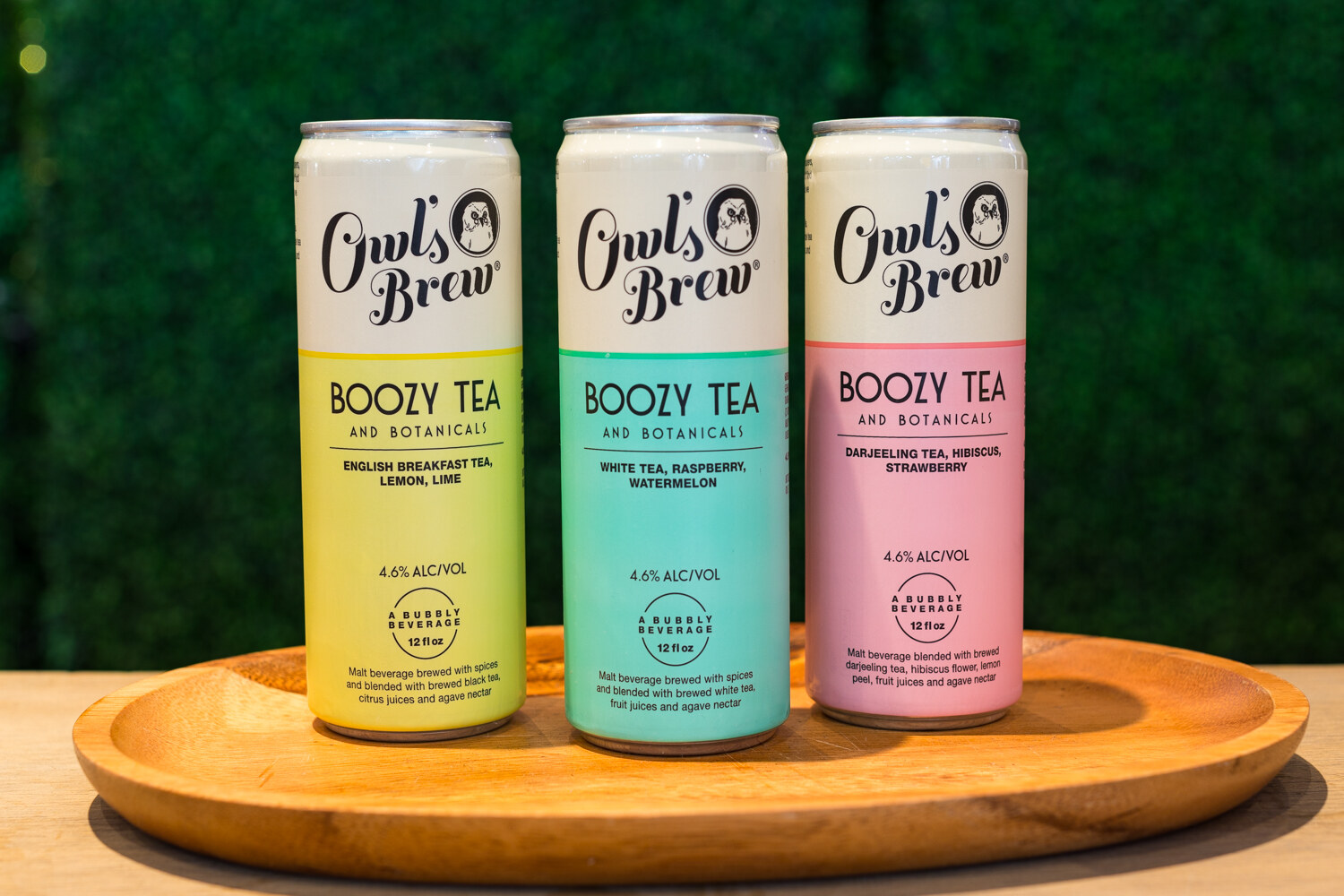 Photo of three cans of Owl's Brew boozy tea on a wooden tray.