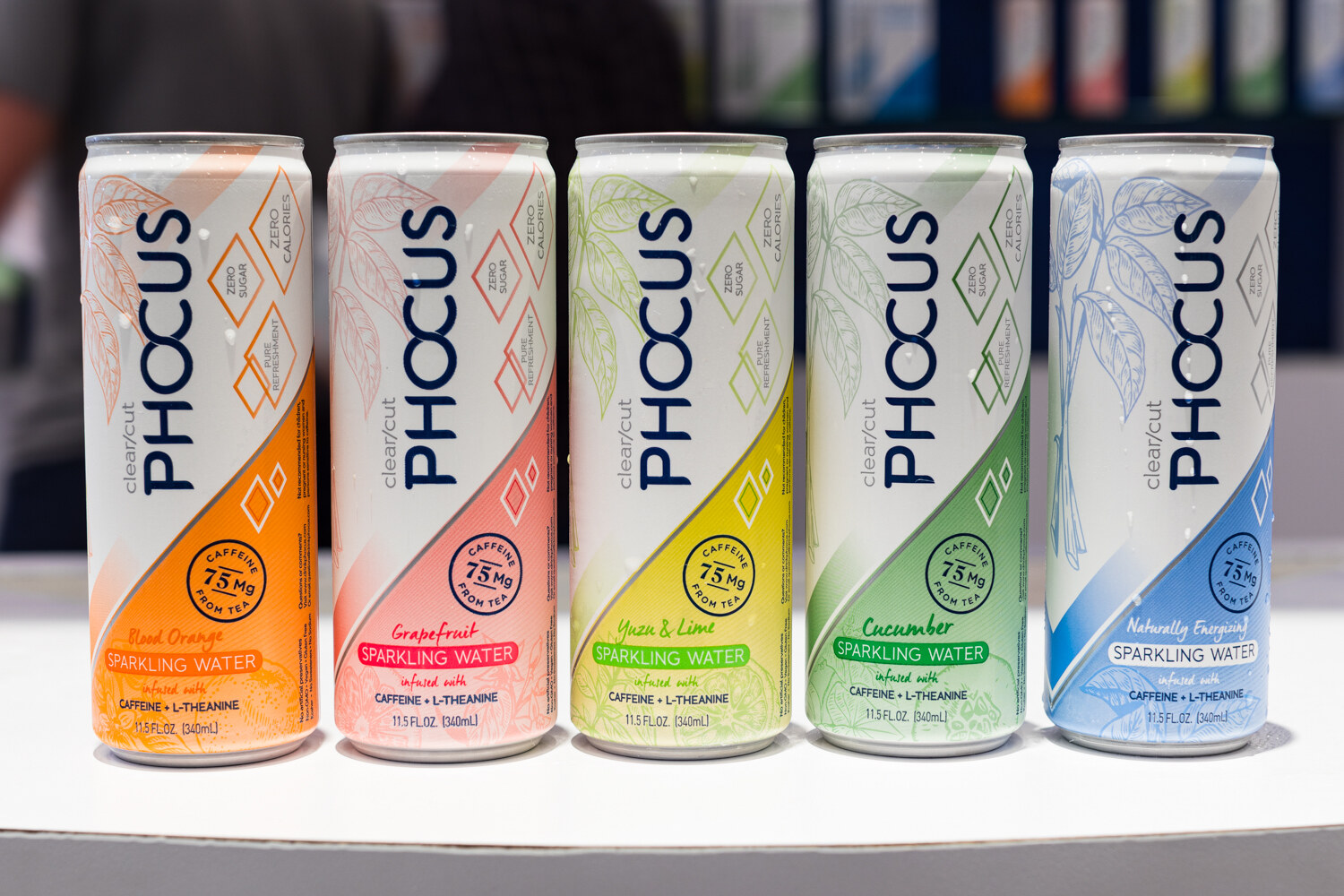 Photo of five slim cans of Phocus sparkling water in orange, pink, yellow, green and blue.