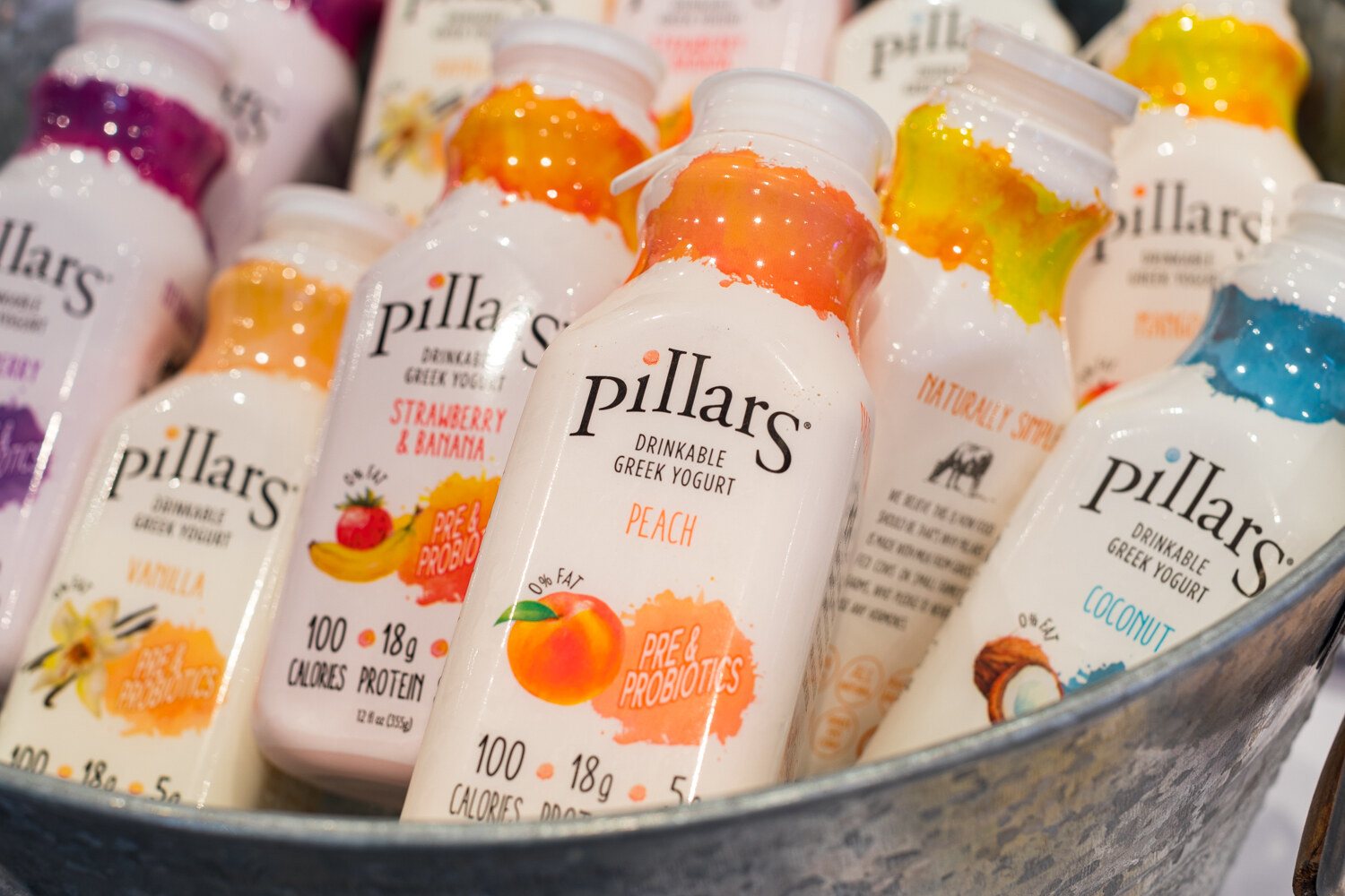 Photo of bottles of Pillars drinkable Greek yogurt in a metal tub.