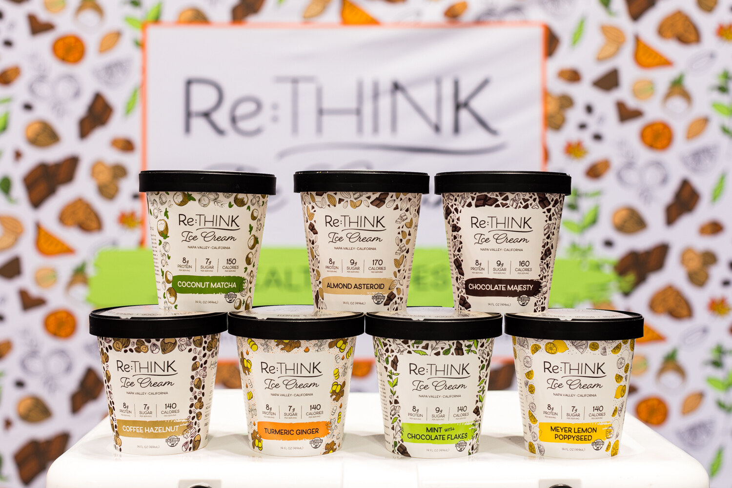 Photo of Re:Think ice cream pints stacked in front of a Re:Think sign.