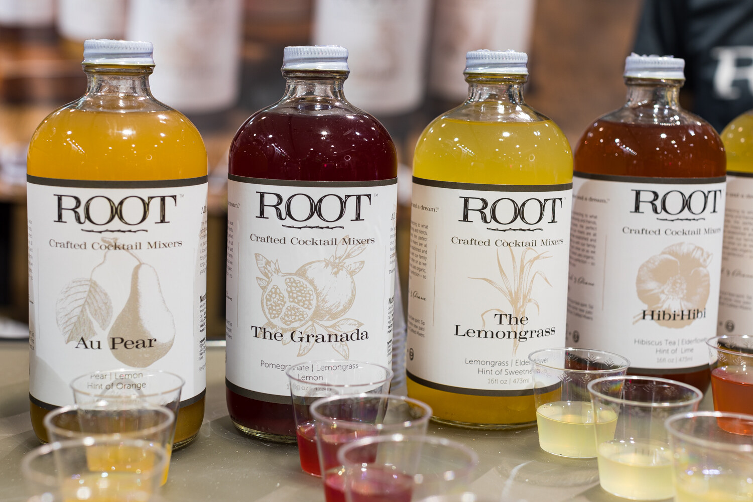Photo of bottles of Root crafted cocktail mixers with sample cups.