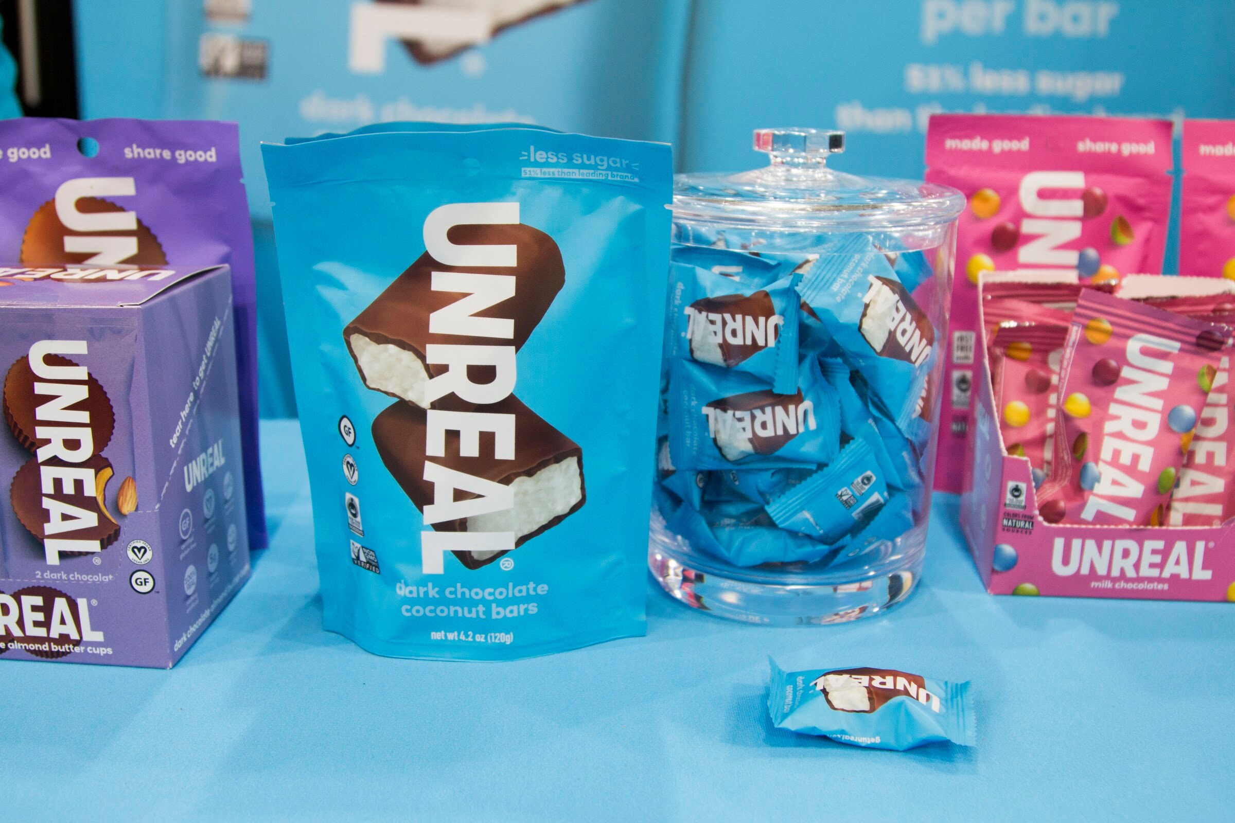 Photo of UNREAL chocolate candy bars and bags on a blue table.